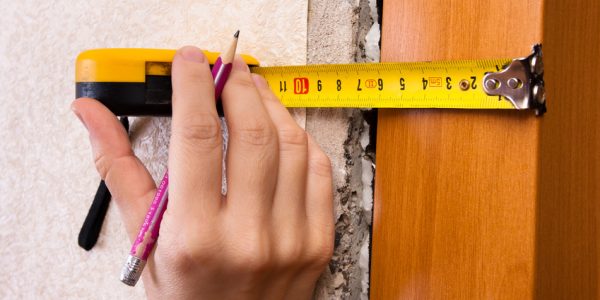 hands measuring wall with tape measure, closeup